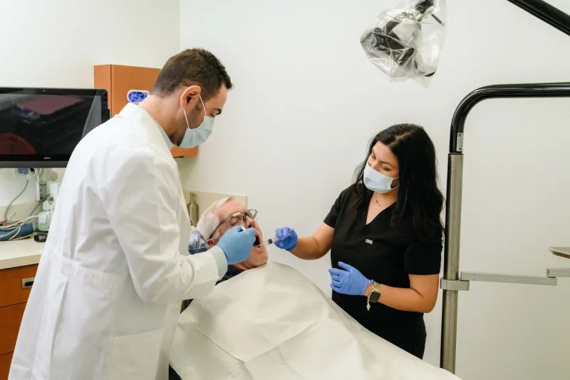 Dr. Zeidan with a female staff during a procedure with an elderly man
