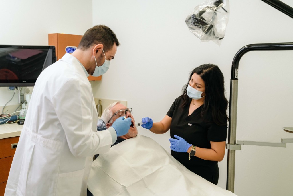 Dr. Zeidan with a female staff during a procedure with an elderly man